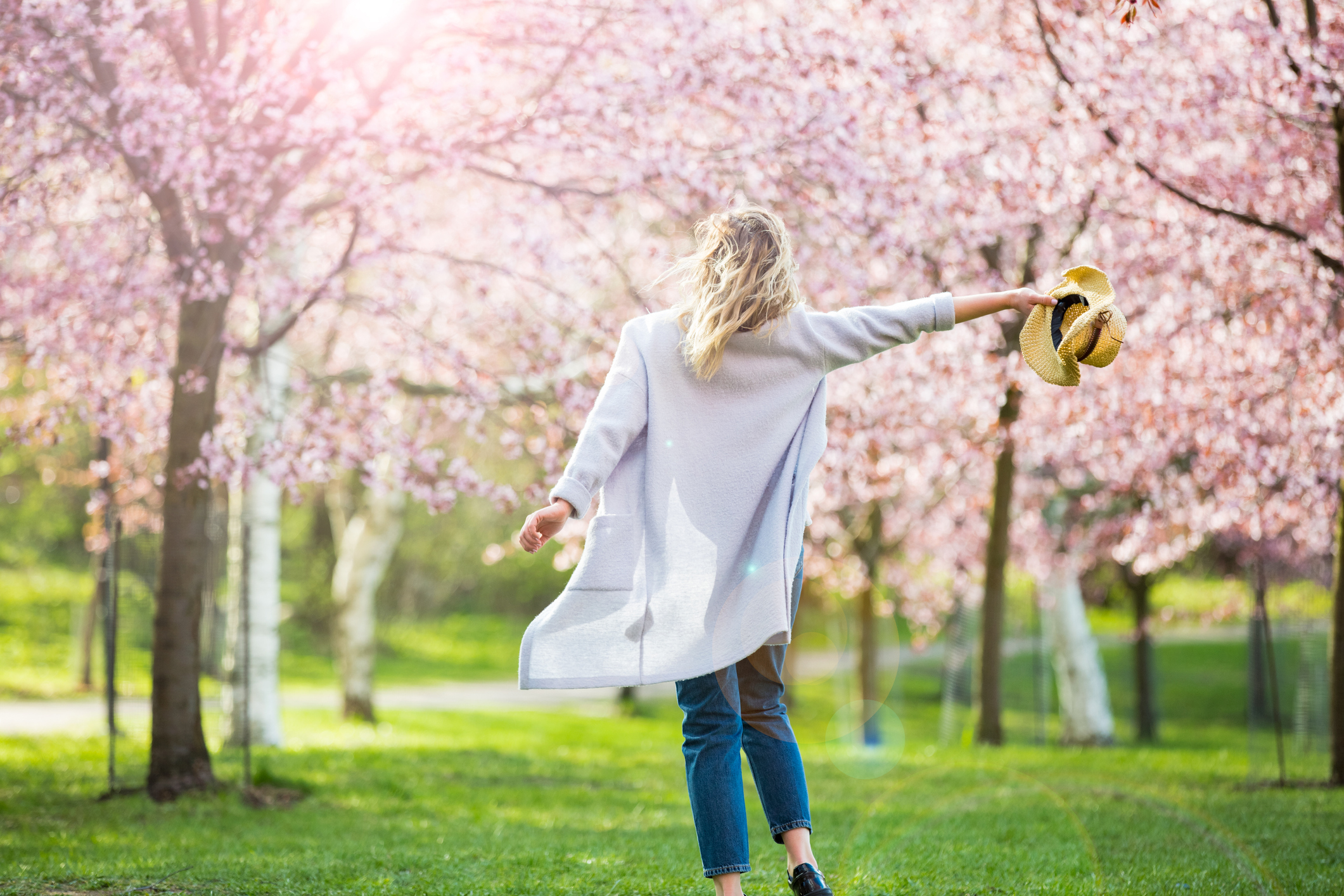 Female taking her hat off dramatically in a cherry blossom forest