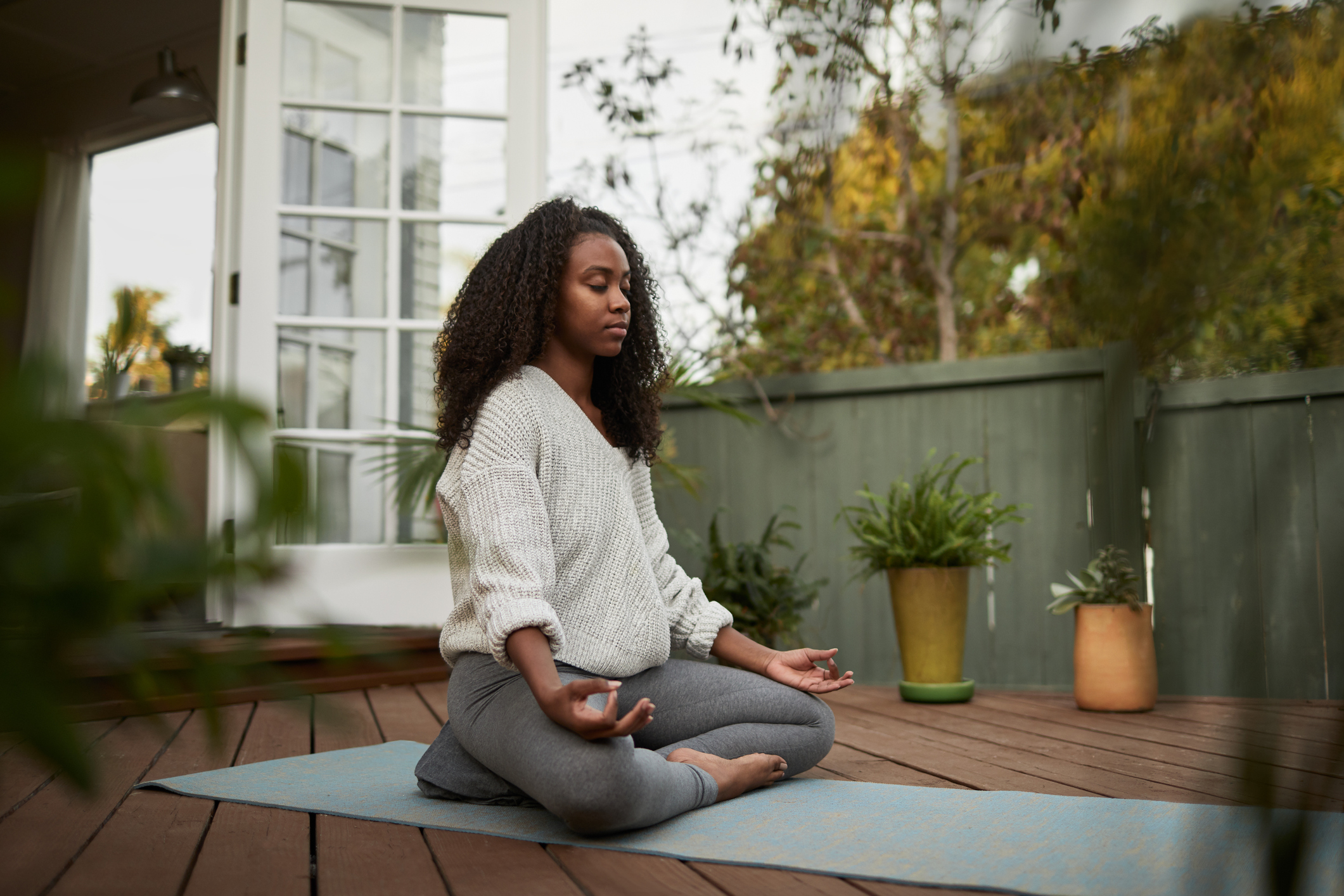 Black woman meditating on outdoor porch